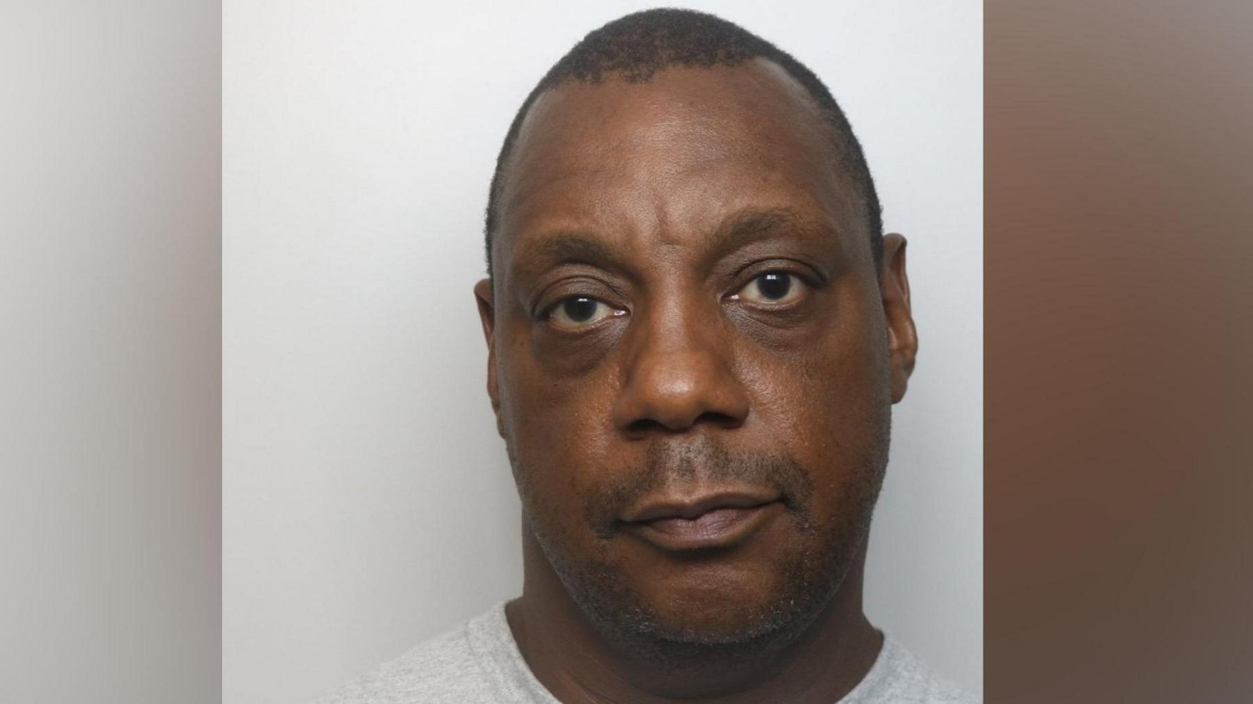 A mugshot of a man in a grey T-shirt looking at the camera.