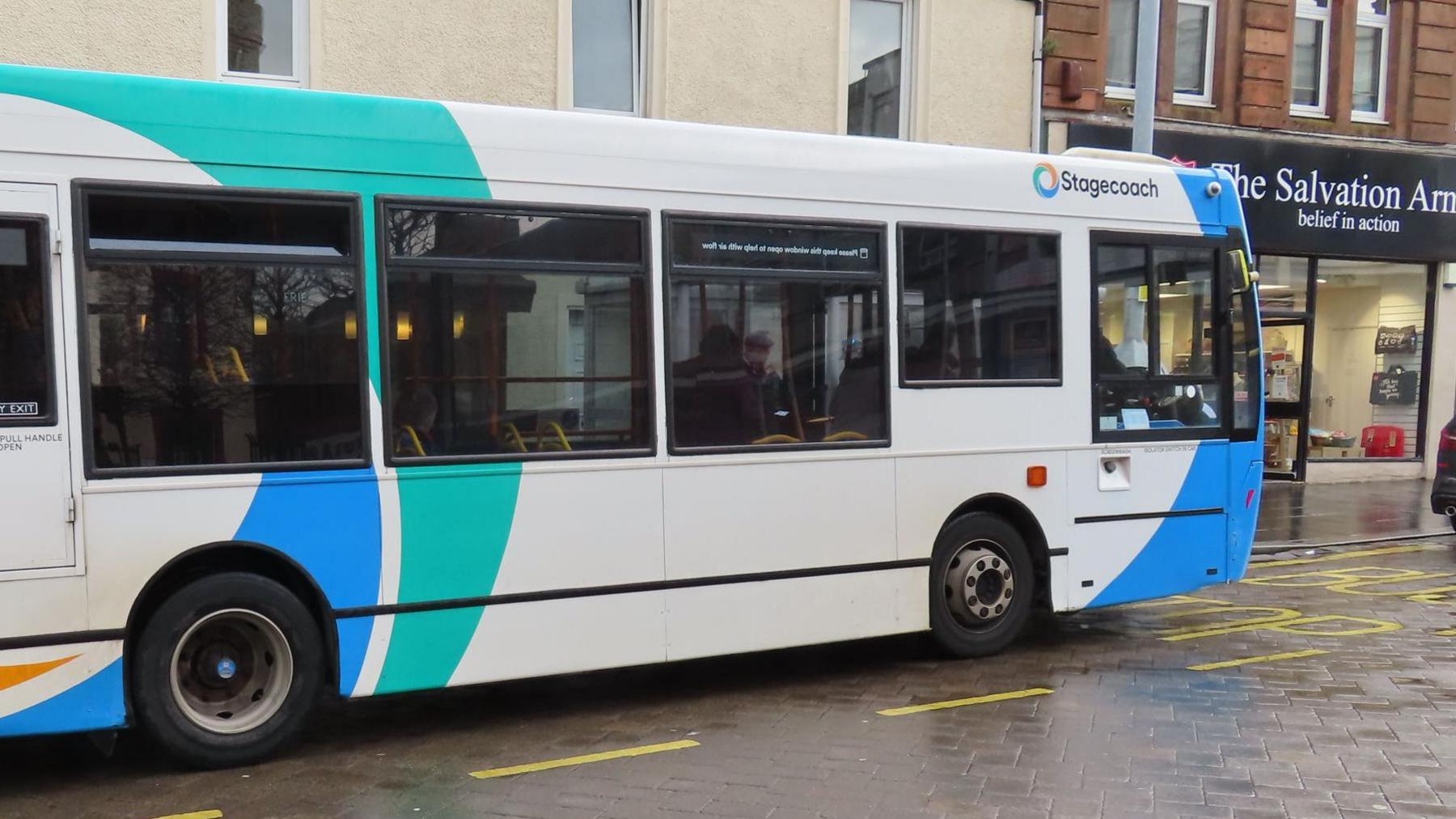 A Stagecoach bus in Dumfries and Galloway sitting in front of shops on a paved roadway