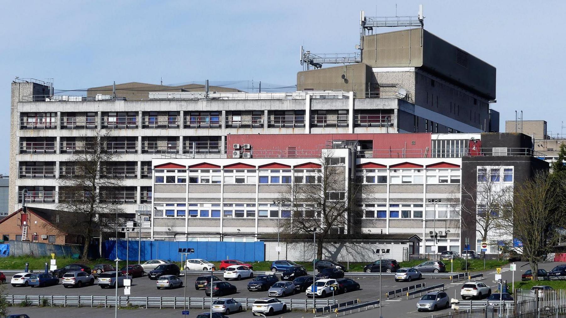 Watford General Hospital exterior, showing a grey concrete building and a car park.