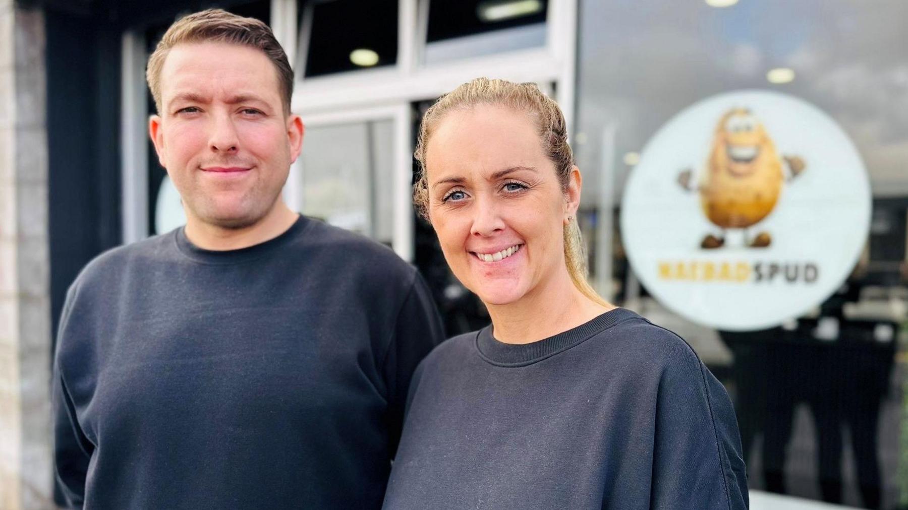 David Groves and Angela McCall, smiling at camera, outside the NaeBadSpud shop.