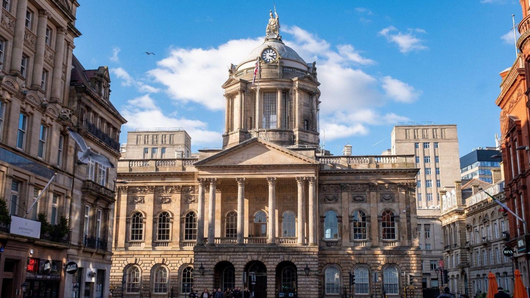 Liverpool Town Hall, a grade two listed Georgian building with three arches at the entrance, pillars above the arches and a dome shaped clock tower.