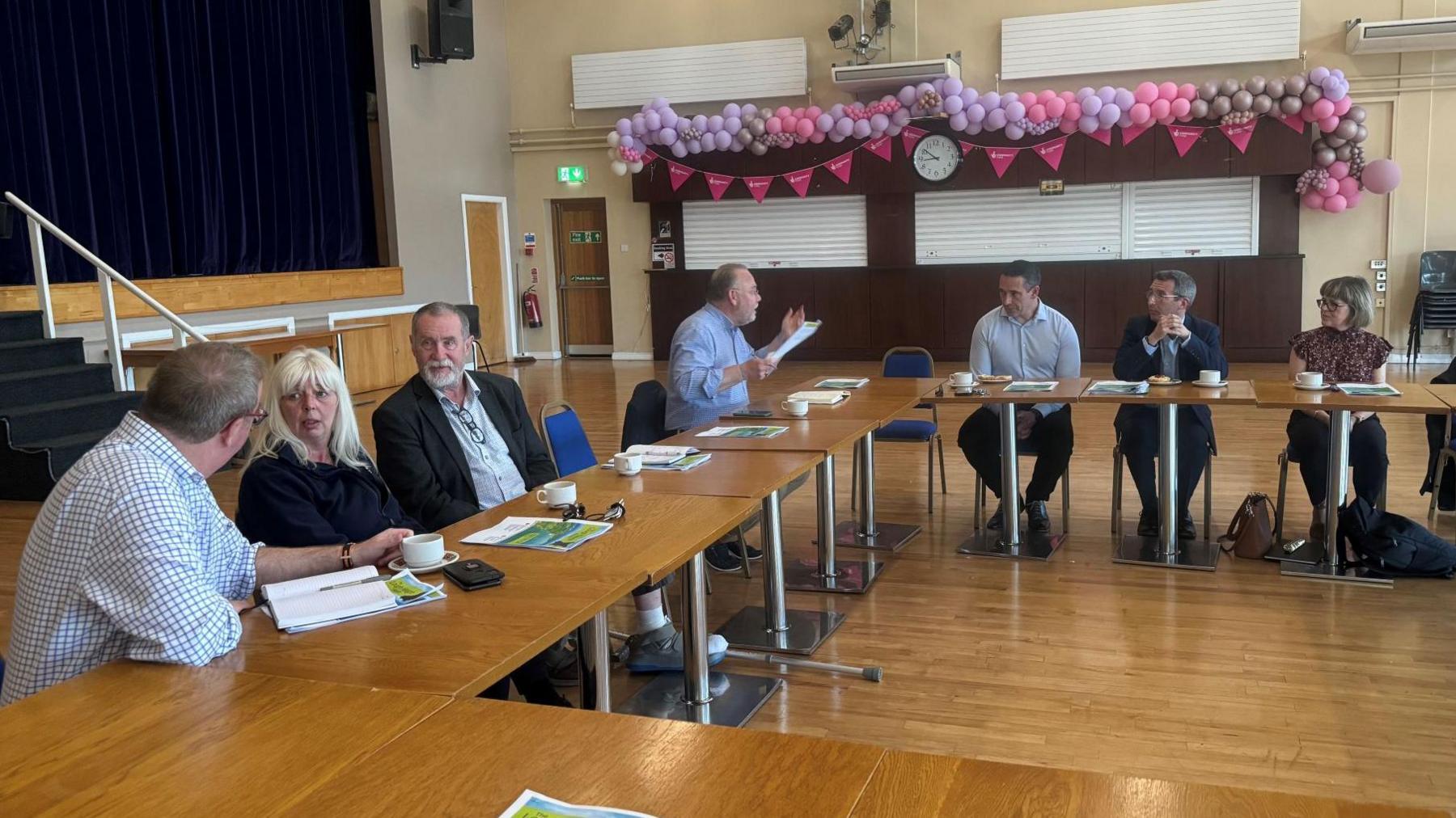 A group of people talk to each other while sitting in a community hall