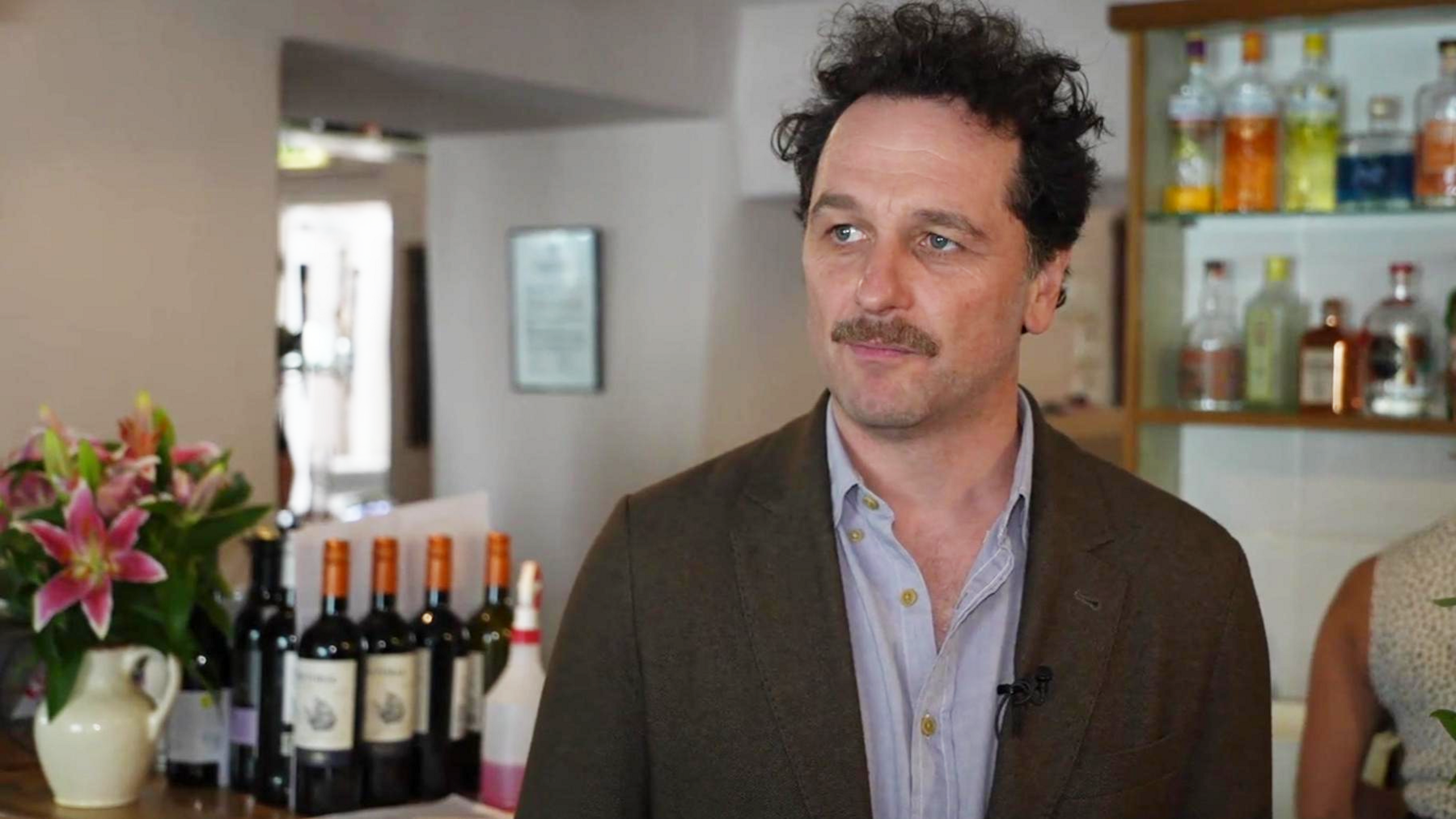 Matthew Rhys in the Glan yr Afon pub in Pennal, Gwynedd. There are bottles on the bar behind him