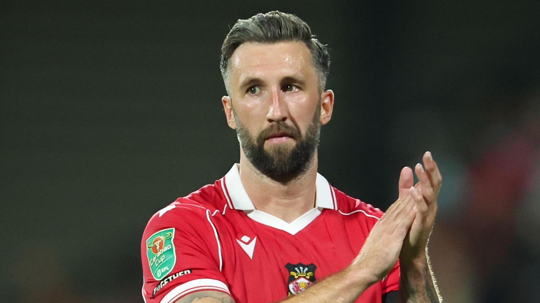 Ollie Palmer standing on the pitch and clapping his hands together at full-time
