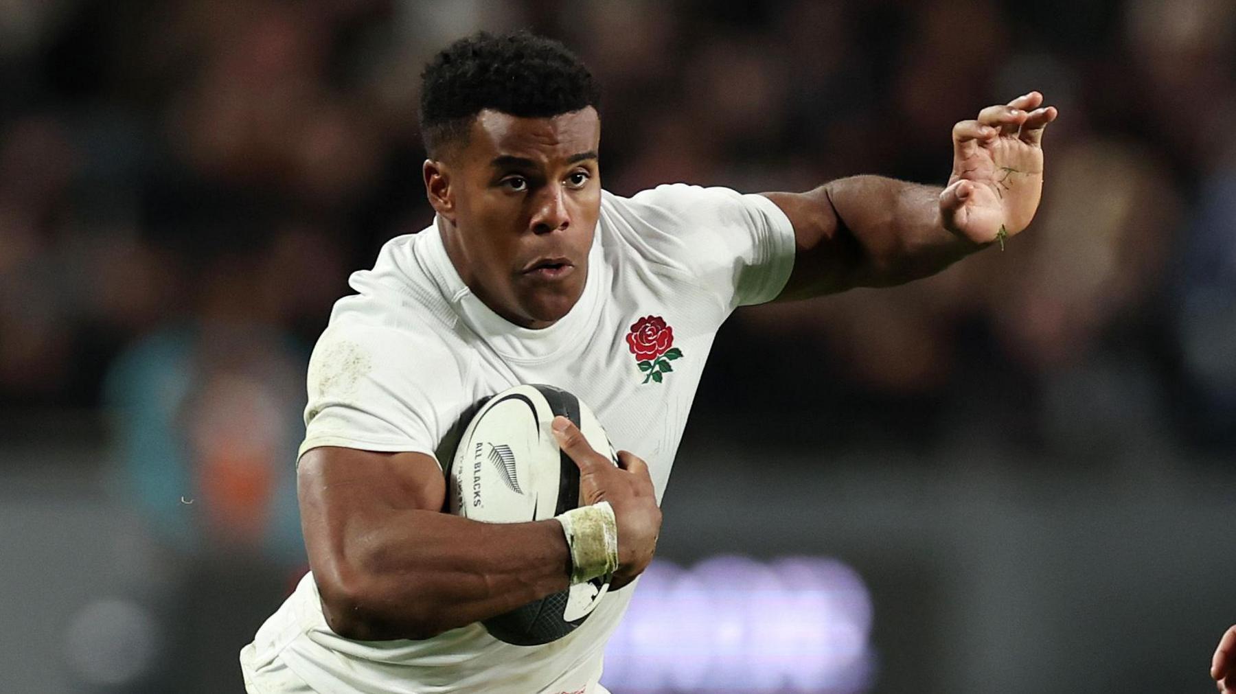 Immanuel Feyi-Waboso in an England shirt carrying a rugby ball