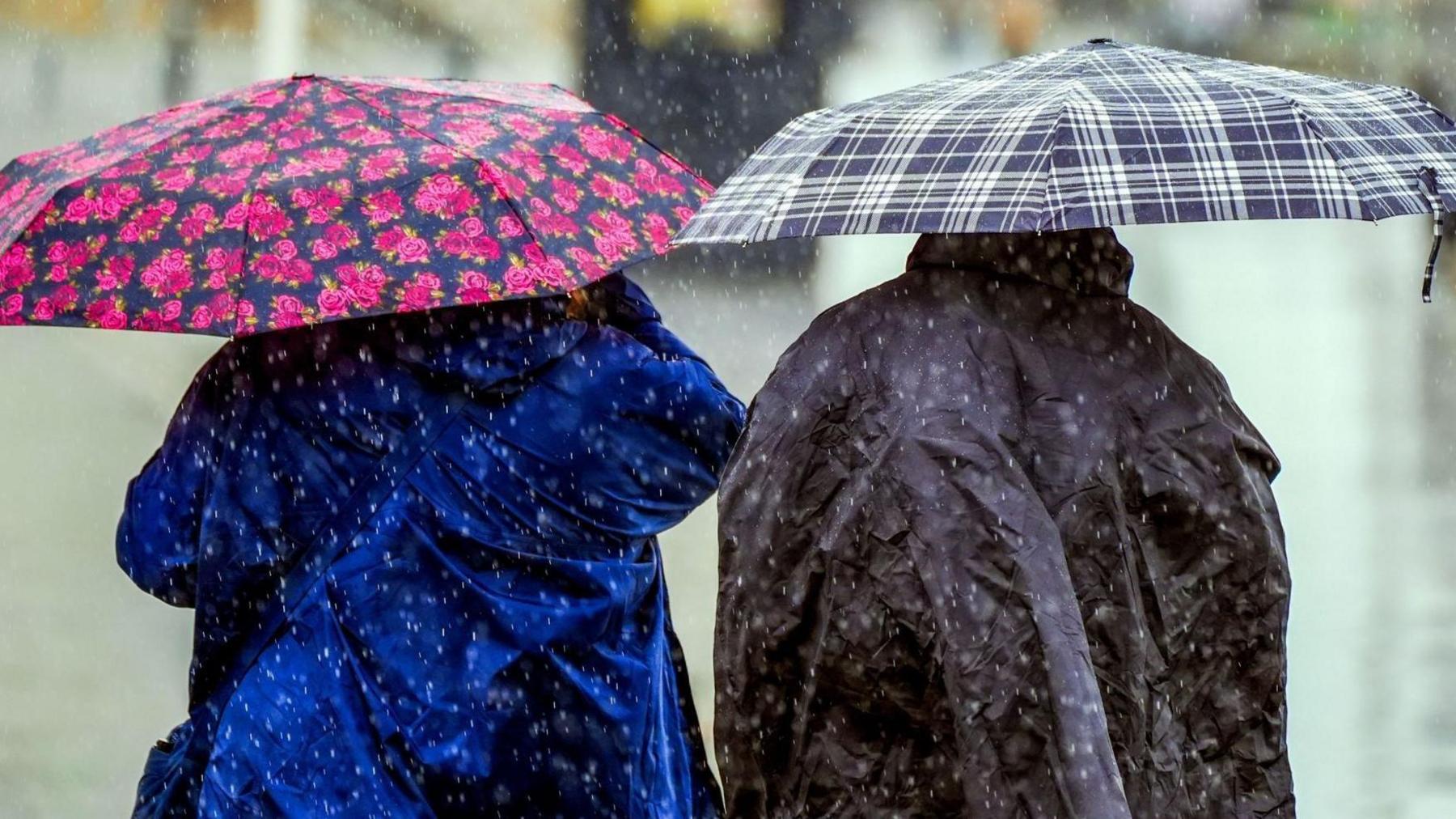 Two people with umbrellas in a downpour