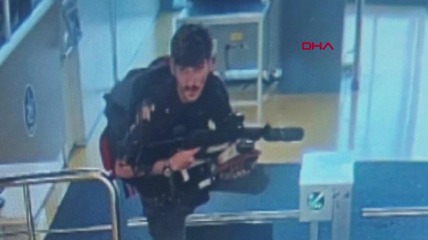 One of the suspects pictured on CCTV climbing over a turnstile holding a gun at the entrance of Turkish Aerospace Industries' headquarters