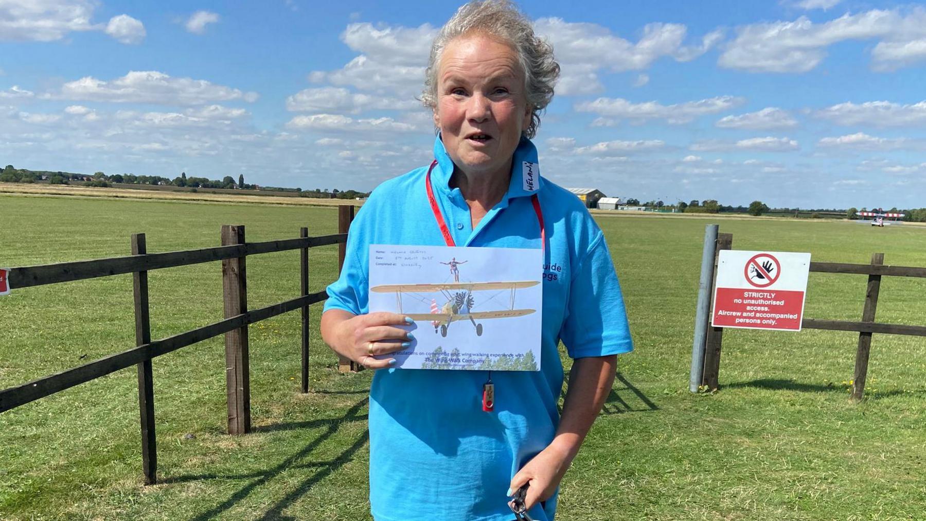 Mel Griffiths after the experience, holding a certificate and smiling at the camera