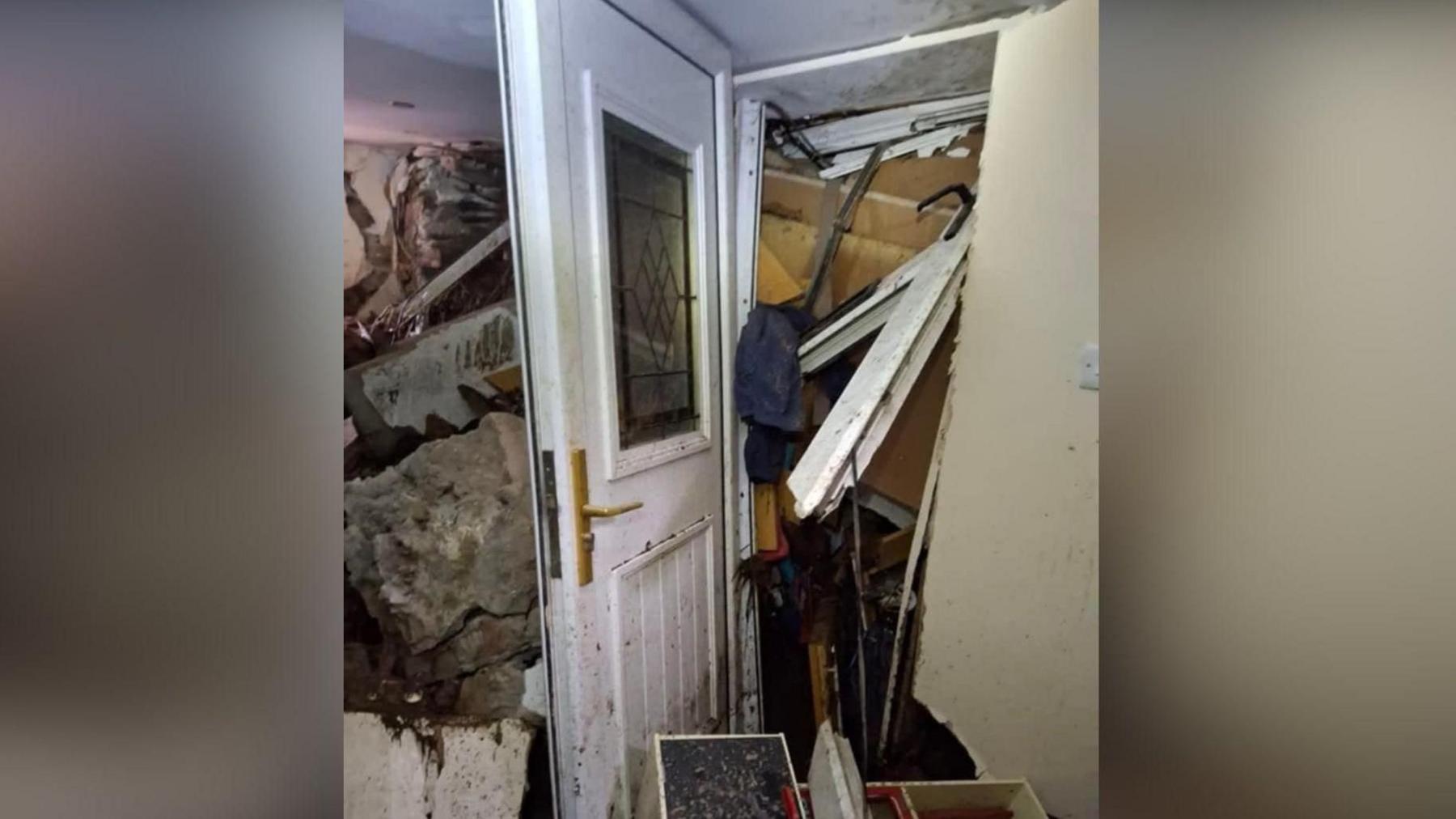 A white front door completely blocked by rubble which has also swept into the home as a result of Storm Bert