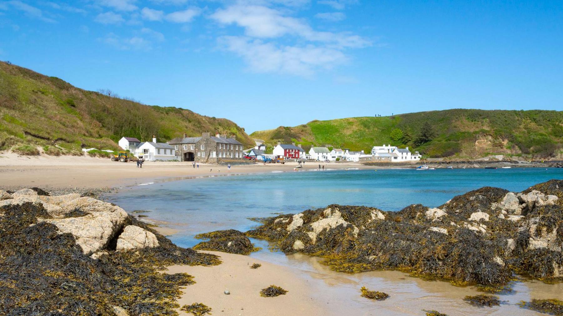 Porthdinllaen, a village on the Llŷn Peninsula in Gwynedd, with the beach at the forefront, and houses and other large buildings in the background