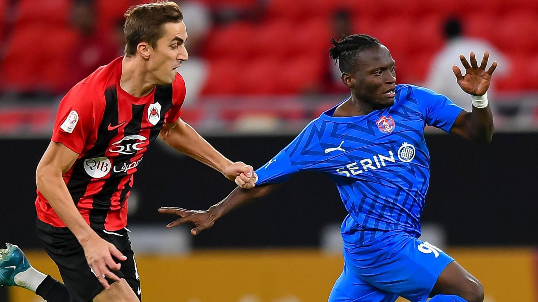 Julien Ariel De Sart (left) of Al Rayyan battles for the ball with Alhassan Koroma (right) of Al Shahaniya by tugging the arm of his shirt