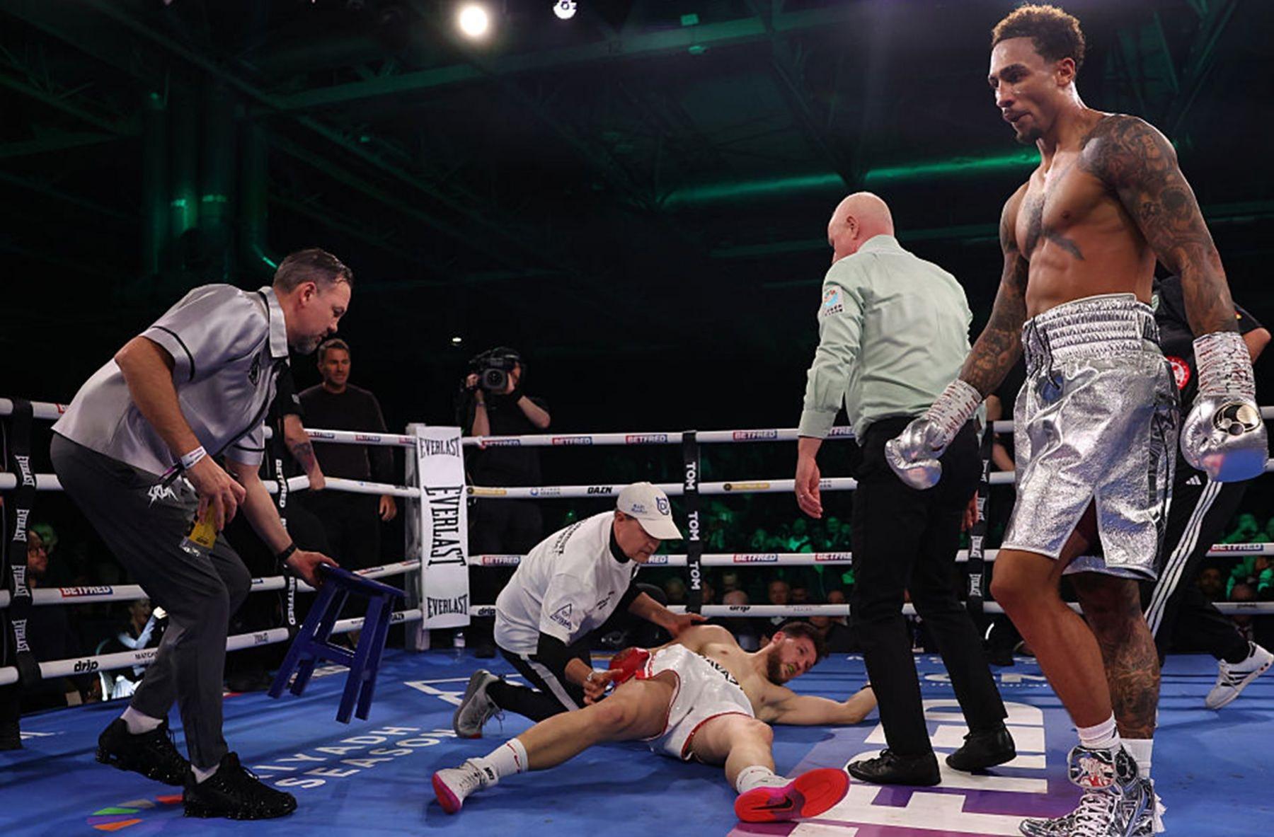 Benjamin Gavazi is on the canvas of a boxing ring as Ben Whittaker walks away