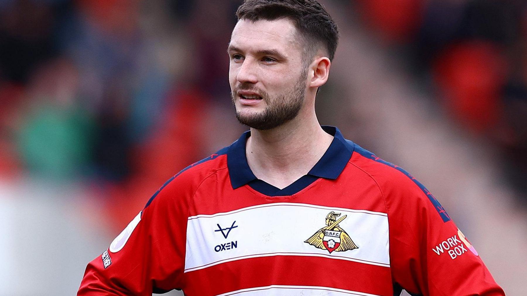 Luke Molyneux in action for Doncaster Rovers in their red and white hooped home jersey