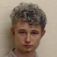 A police mugshot of Cameron Allan in which he is looking directly at the camera. He has light curly hair and a small amount of facial hair on his chin and is wearing a light coloured shirt.