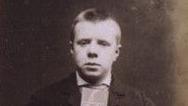 A mugshot of a young man, John Porter. He has short, cropped hair and is looking forlornly into the camera. The image is in black and white. 