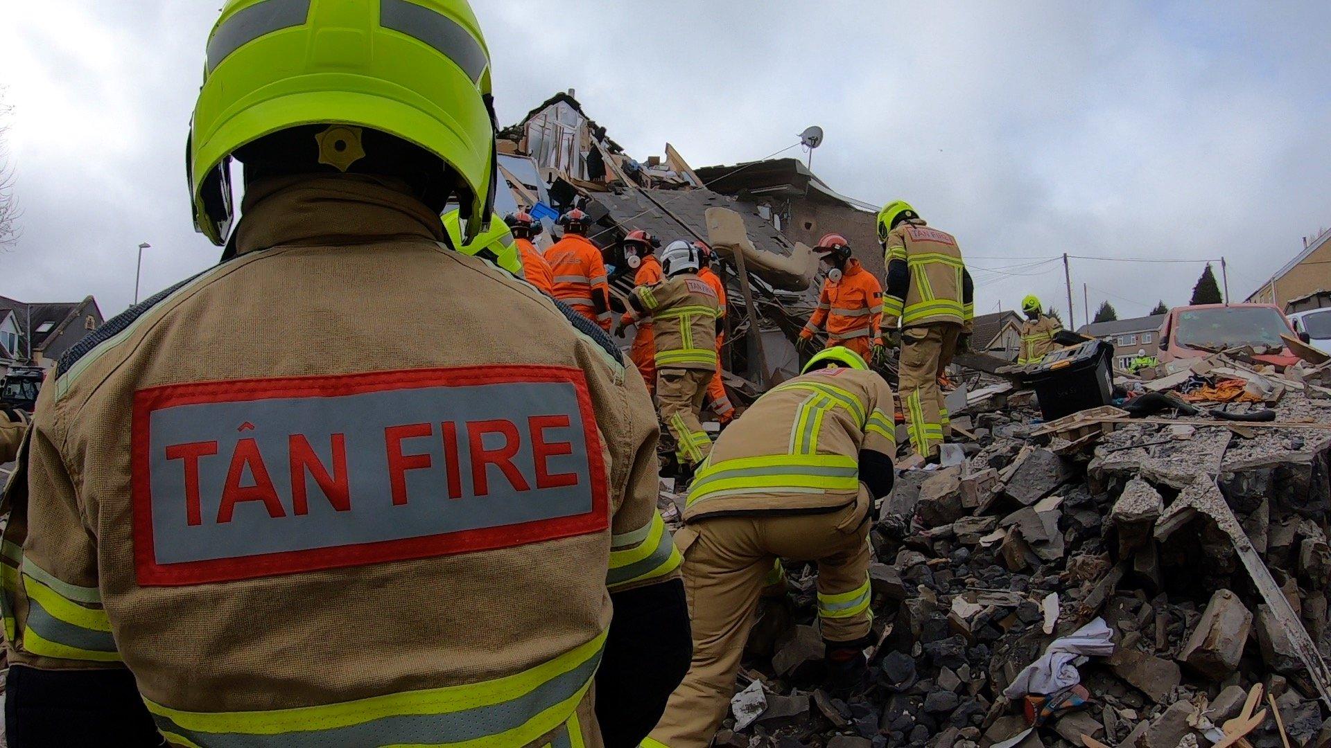 A number of firefighters and search and rescue workers remove the rubble from the site of the explosion