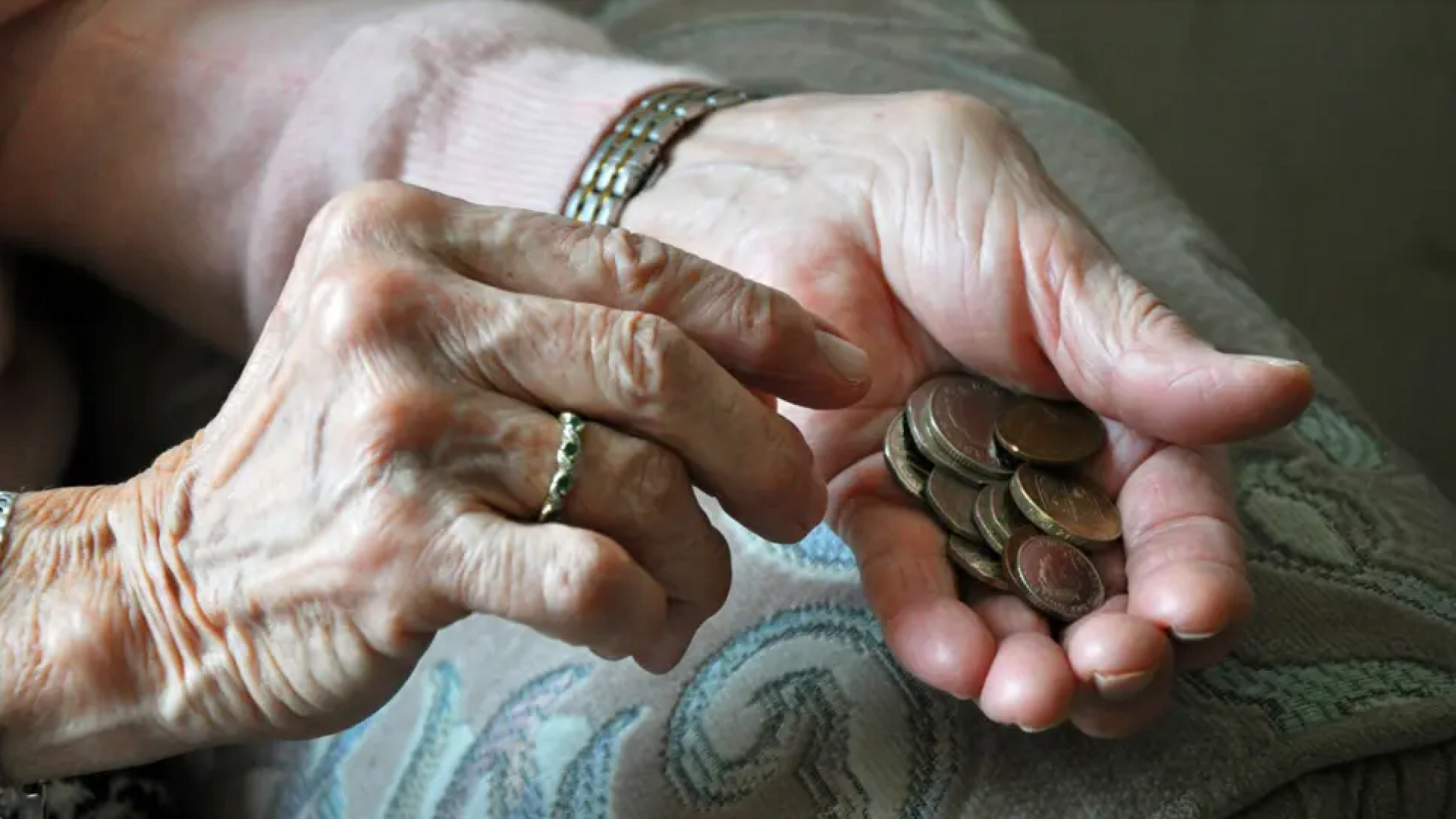 Close-up on elderly person's hands holding small change.