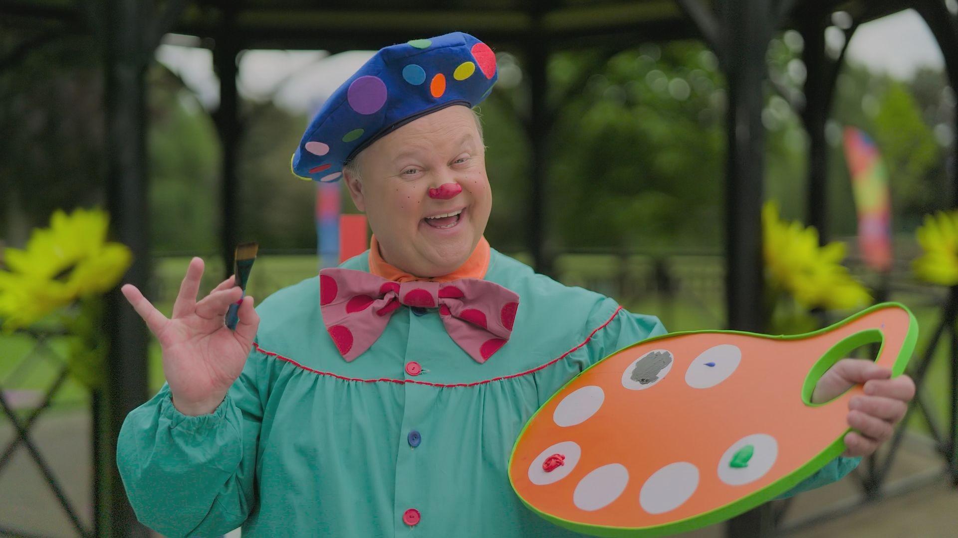 Mr Tumble wearing an artist's smock and holding a paint pallette