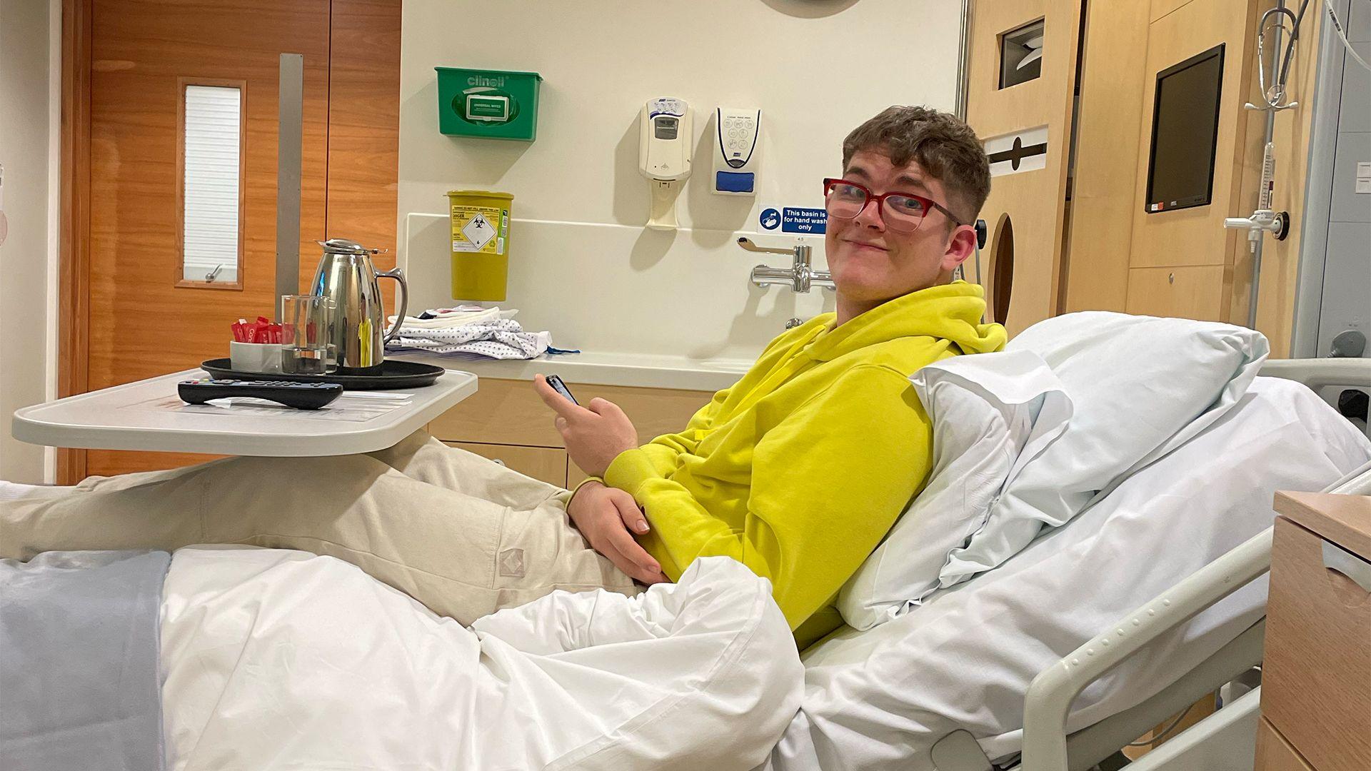 19-year-old Thomas Rennie sitting on a hospital bed.