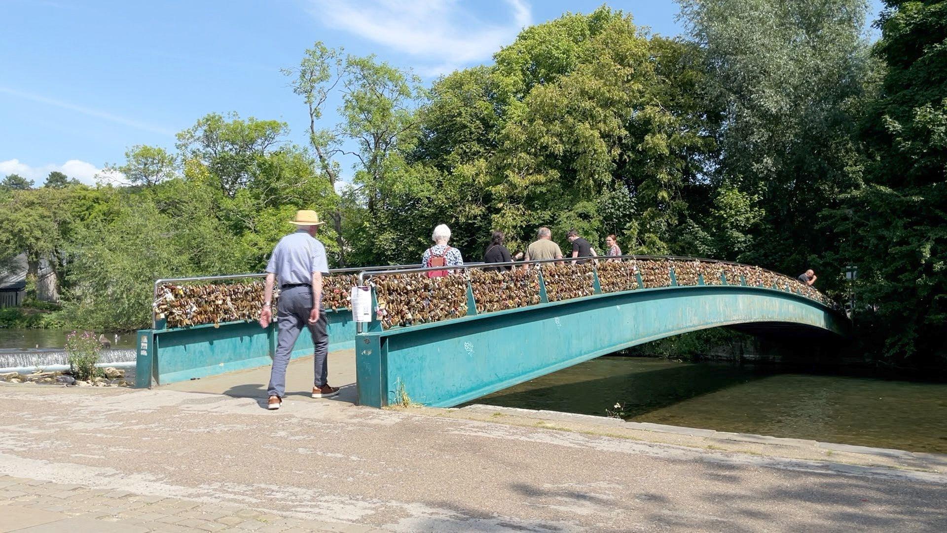 People walking over Weir Bridge in Bakewell when it was still covered in padlocks