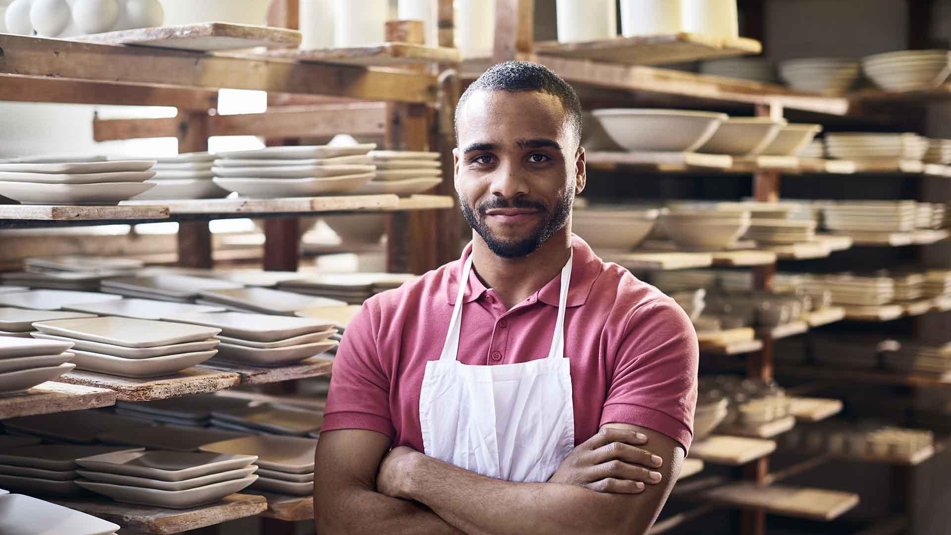 Worker standing in front of shelves of crockery