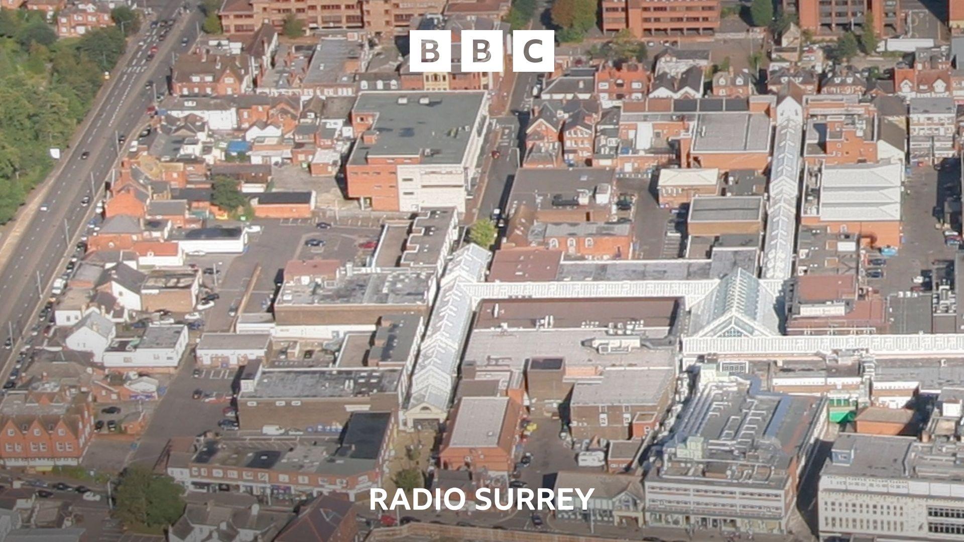 An aerial view of a town centre. There are red brick modern buildings of varying heights, with some flat and some pitched roofs.