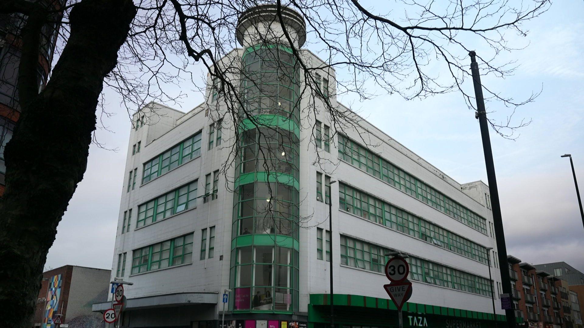 The exterior of an Art Deco-style building, Borden Court, in Liverpool's London Road. It is white with green painted windows. 