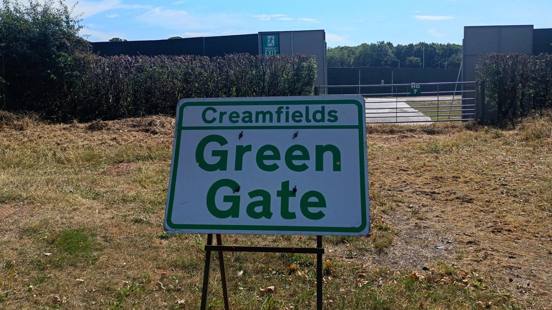 A Creamfields Green Gate sign on grass by the main road by the site