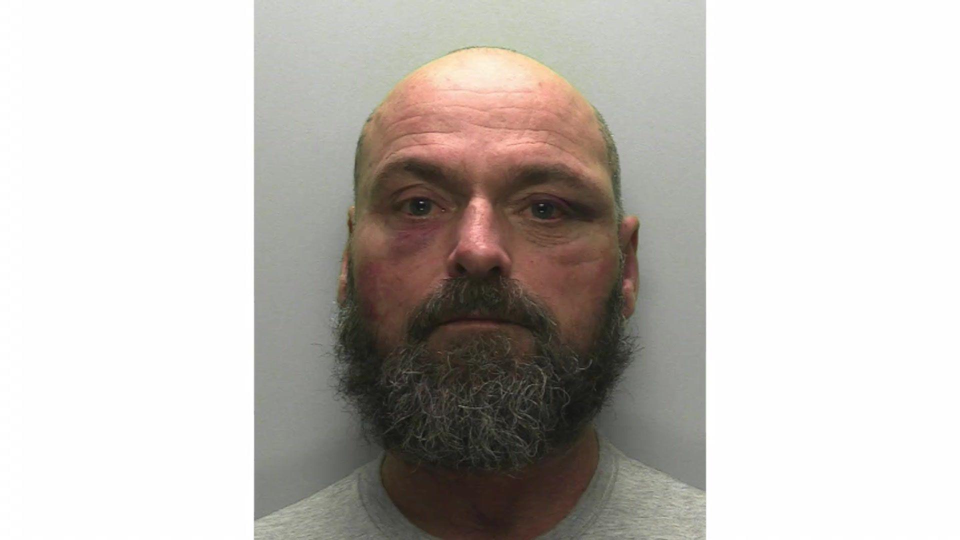 Police mugshot of Shaun McCormick, a man with large dark and grey beard and bald head