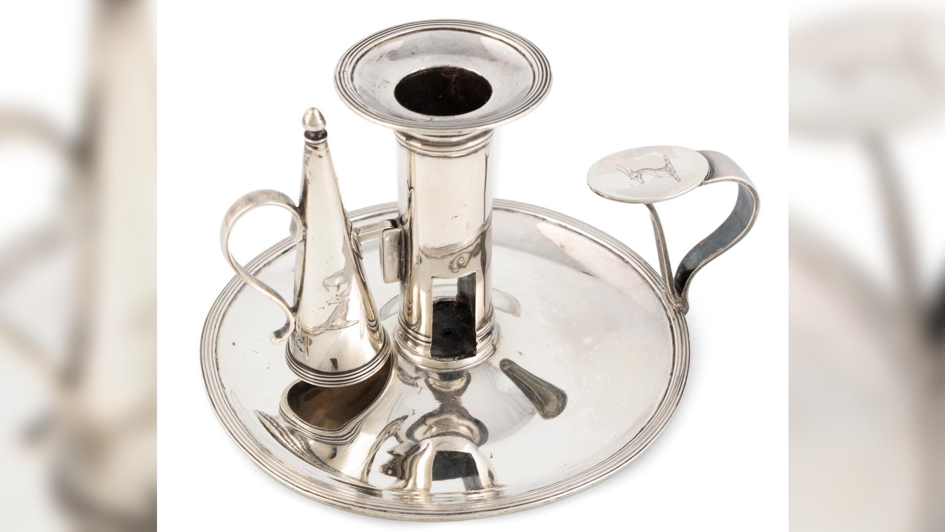 A silver chamberstick and snuffer, with a plate at the bottom. It is against a white background.