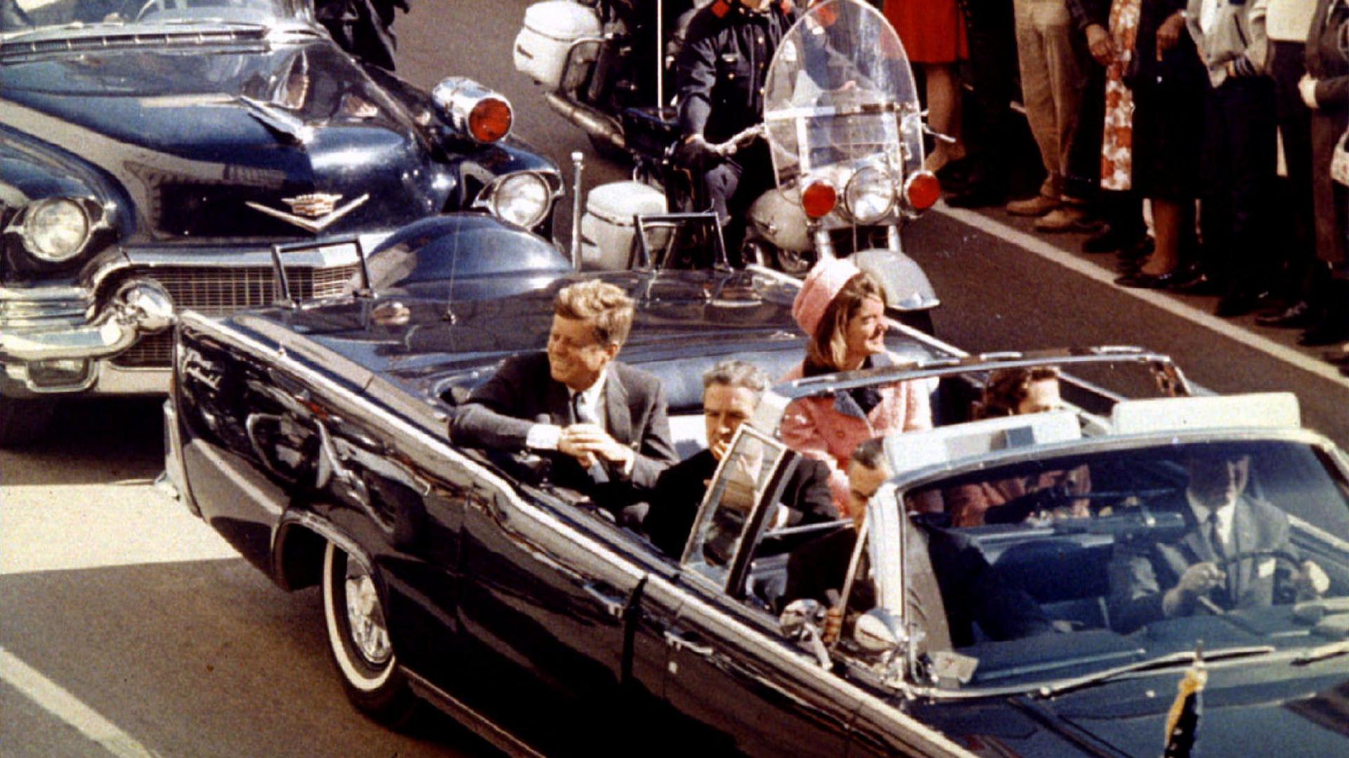 A general view of the car carrying JFK and Jackie Kennedy, filing past a crowd of onlookers