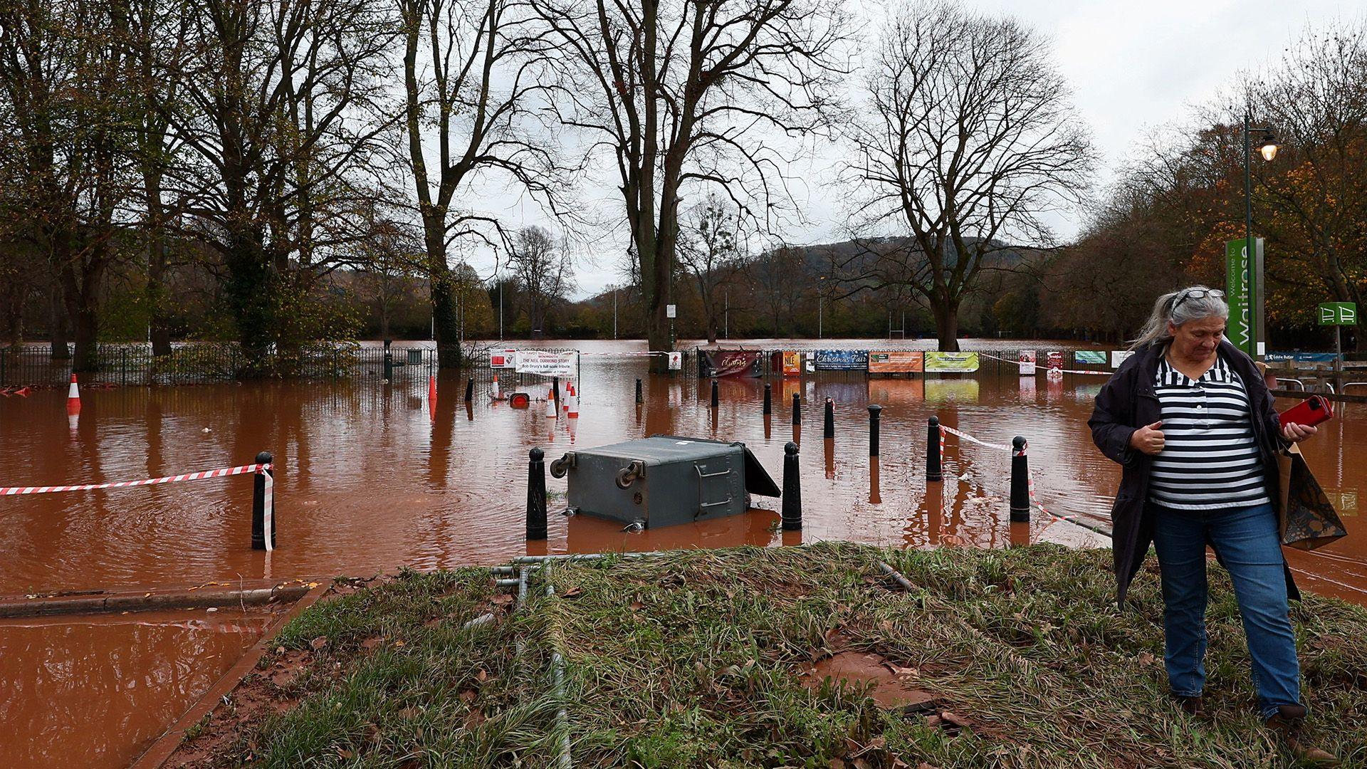 A person walks through a flooded area after severe flooding caused by Storm Claudia