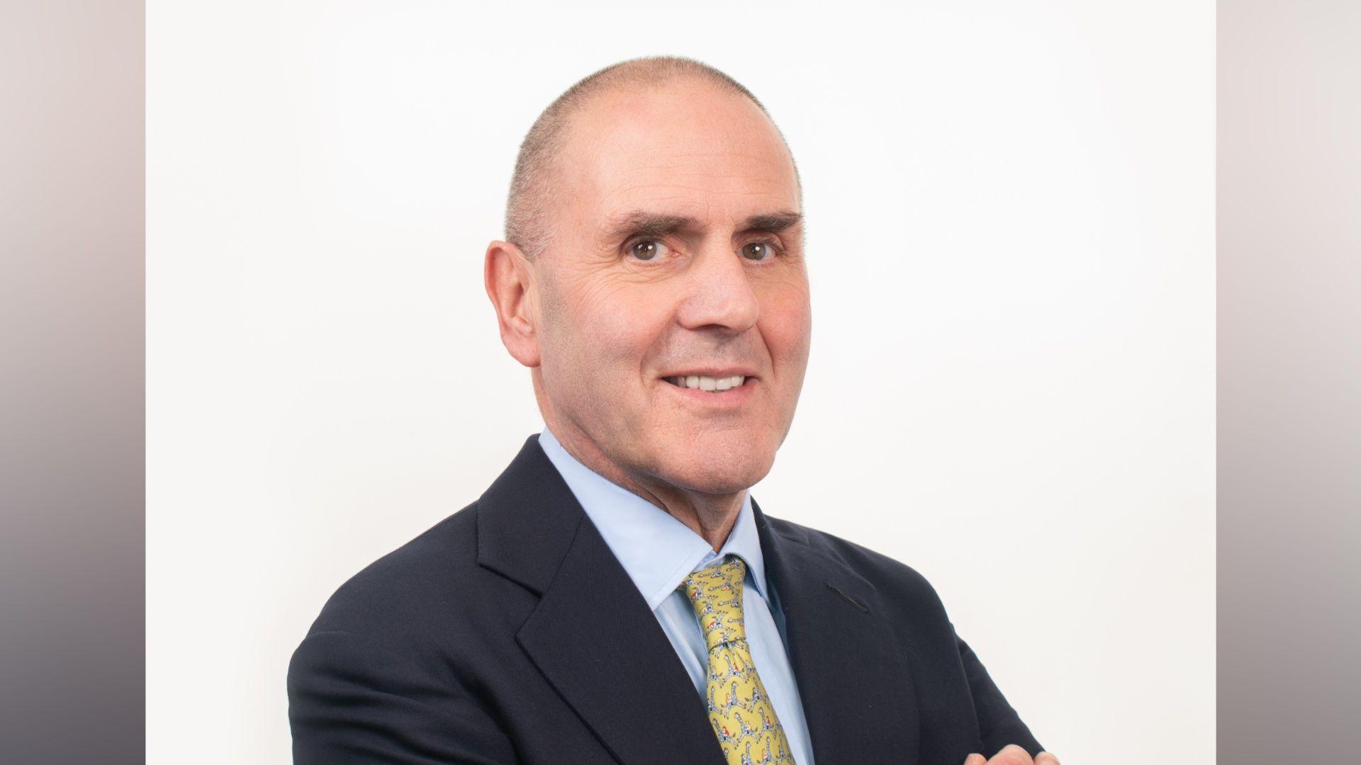 A headshot of Martin Healy. He is wearing a dark suit and yellow tie.