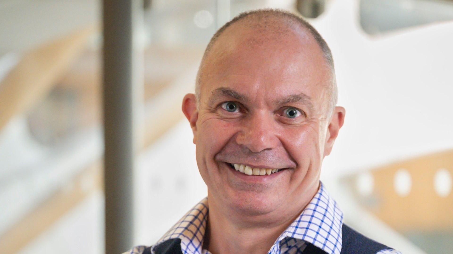 University of Exeter's Prof David Strain smiles broadly. He is wearing a blue and white chequered shirt and a grey waistcoat.