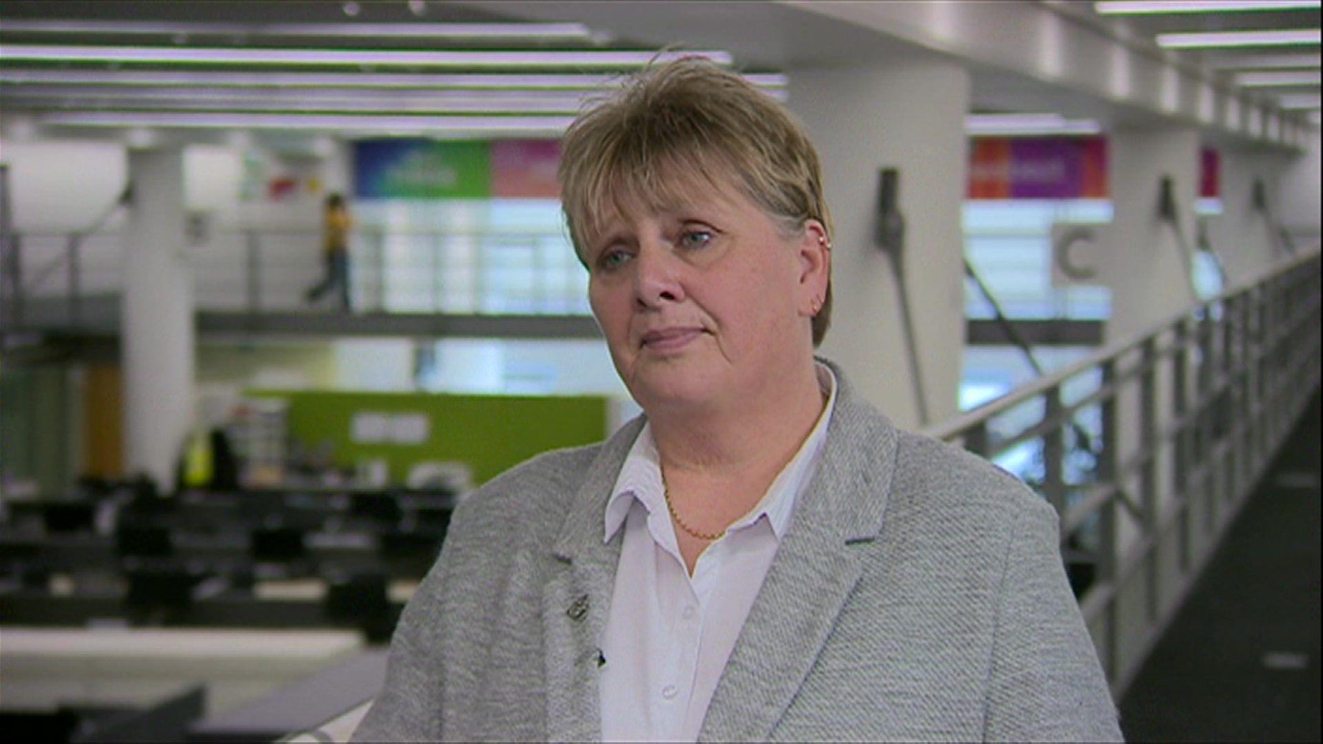 Lezley Picton standing on a balcony at BBC Birmingham's Mailbox studios, being interviewed while wearing a grey blazer and white shirt.