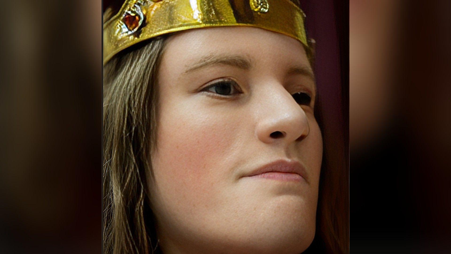 A recreation of Richard III: a man with long brown hair and brown eyes wearing a crown