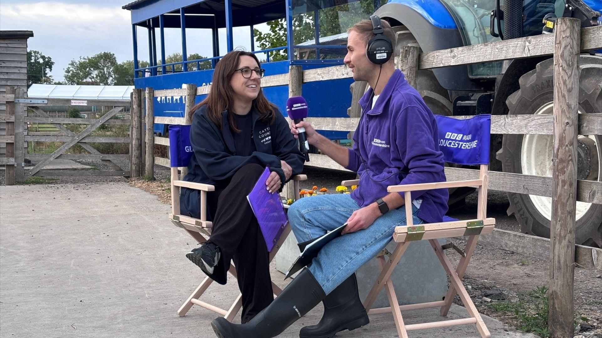 Two people chatting with a mircophone on BBC Gloucestershire deck chairs.