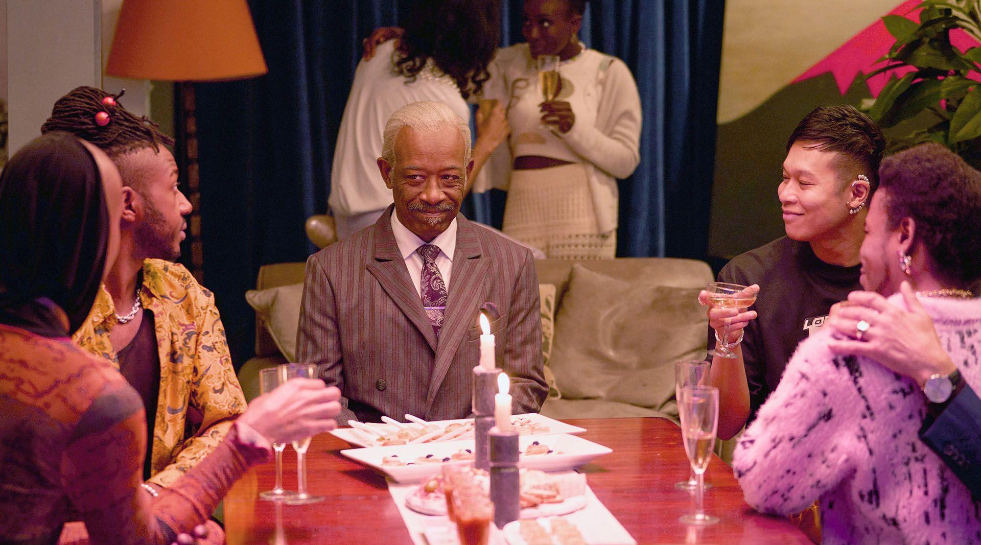 a dinner party featuring lennie james in character with multiple young people