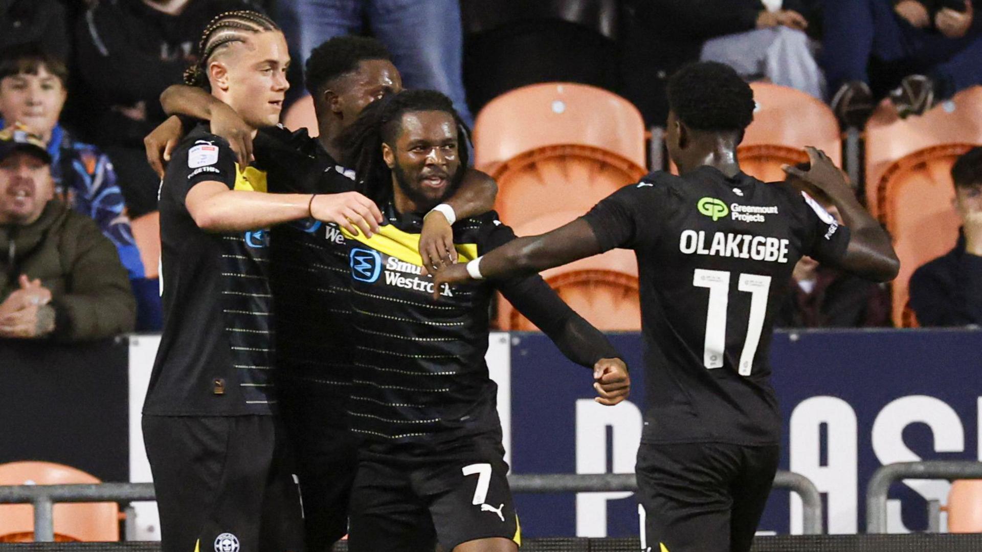 Wigan winger Dion Rankine celebrates with teammates after scoring against Blackpool