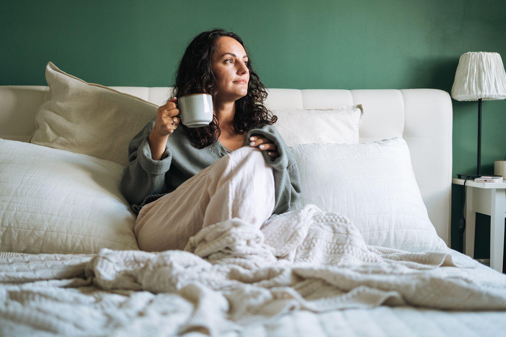 A woman in bed drinking a cup of tea