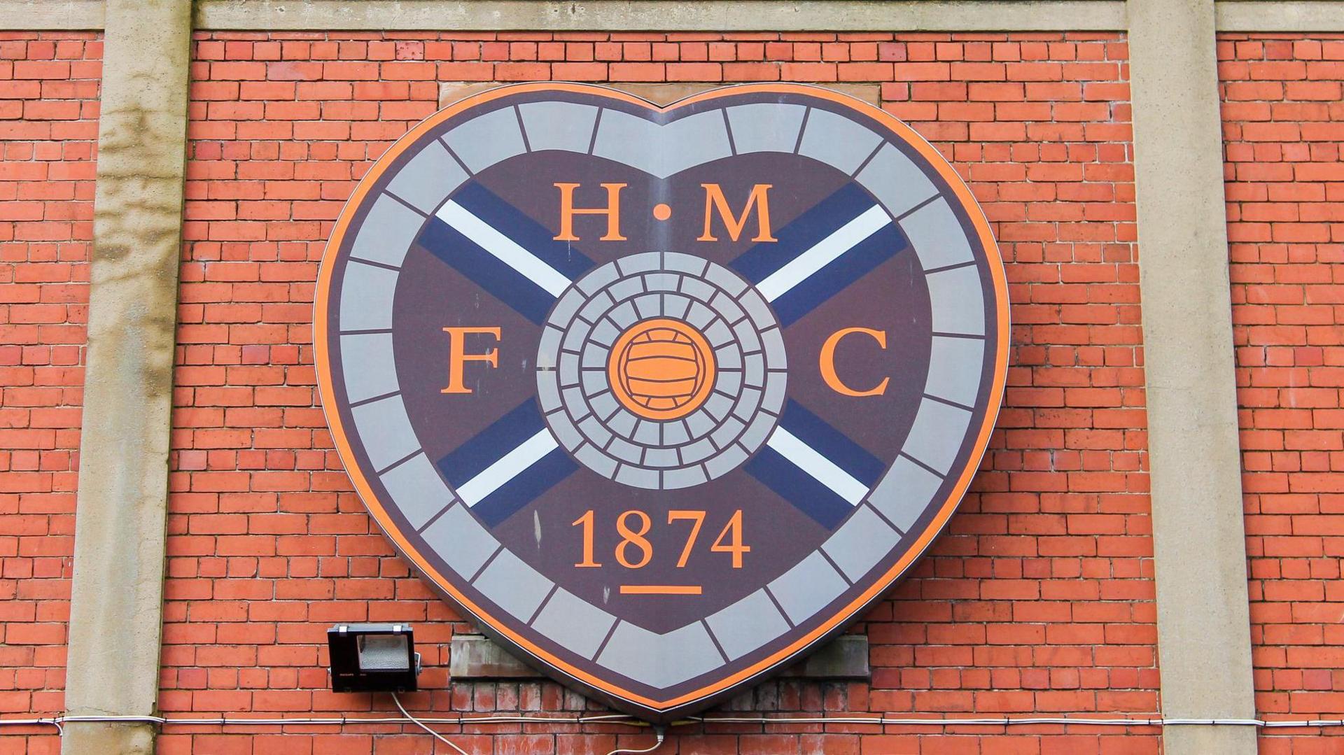 A photo of Heart of Midlothian FC's crest on a brick wall outside Tynecastle Park.