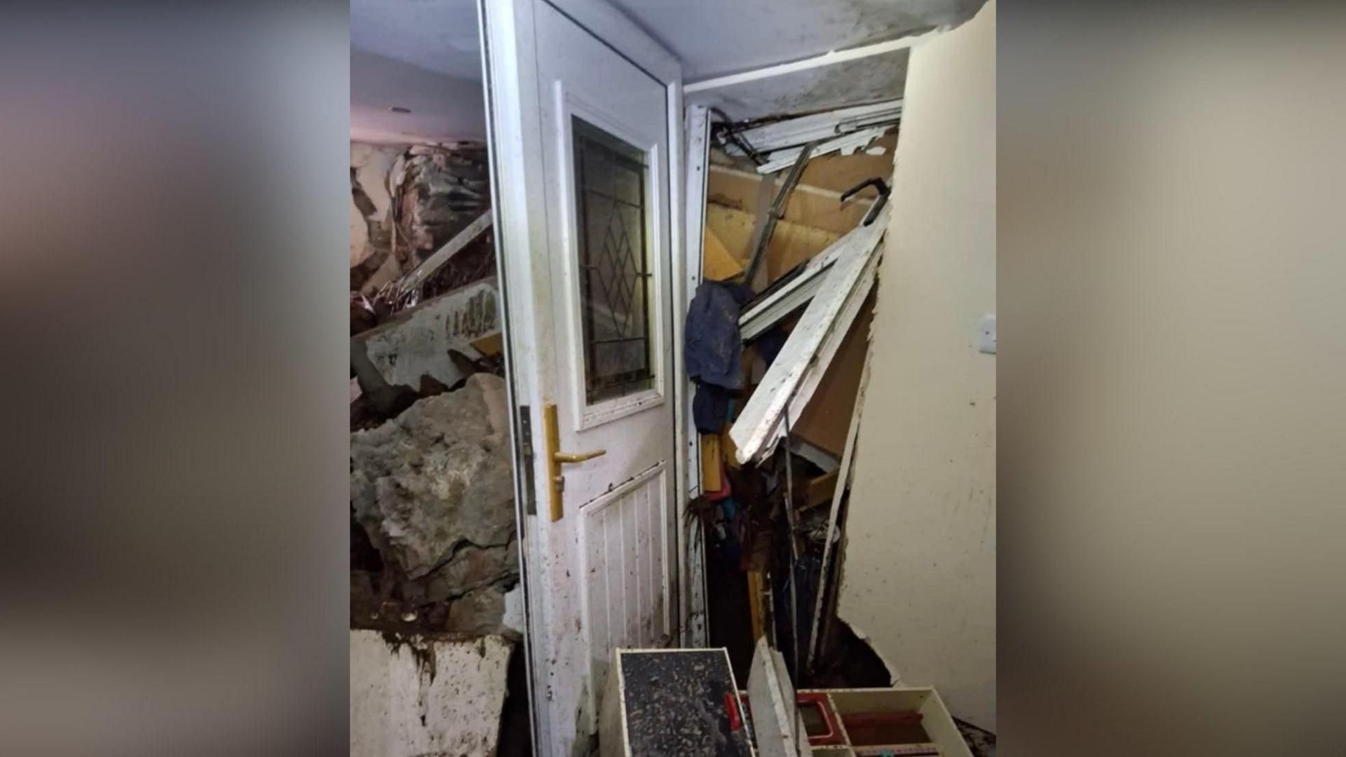 A white front door completely blocked by rubble which has also swept into the home as a result of Storm Bert