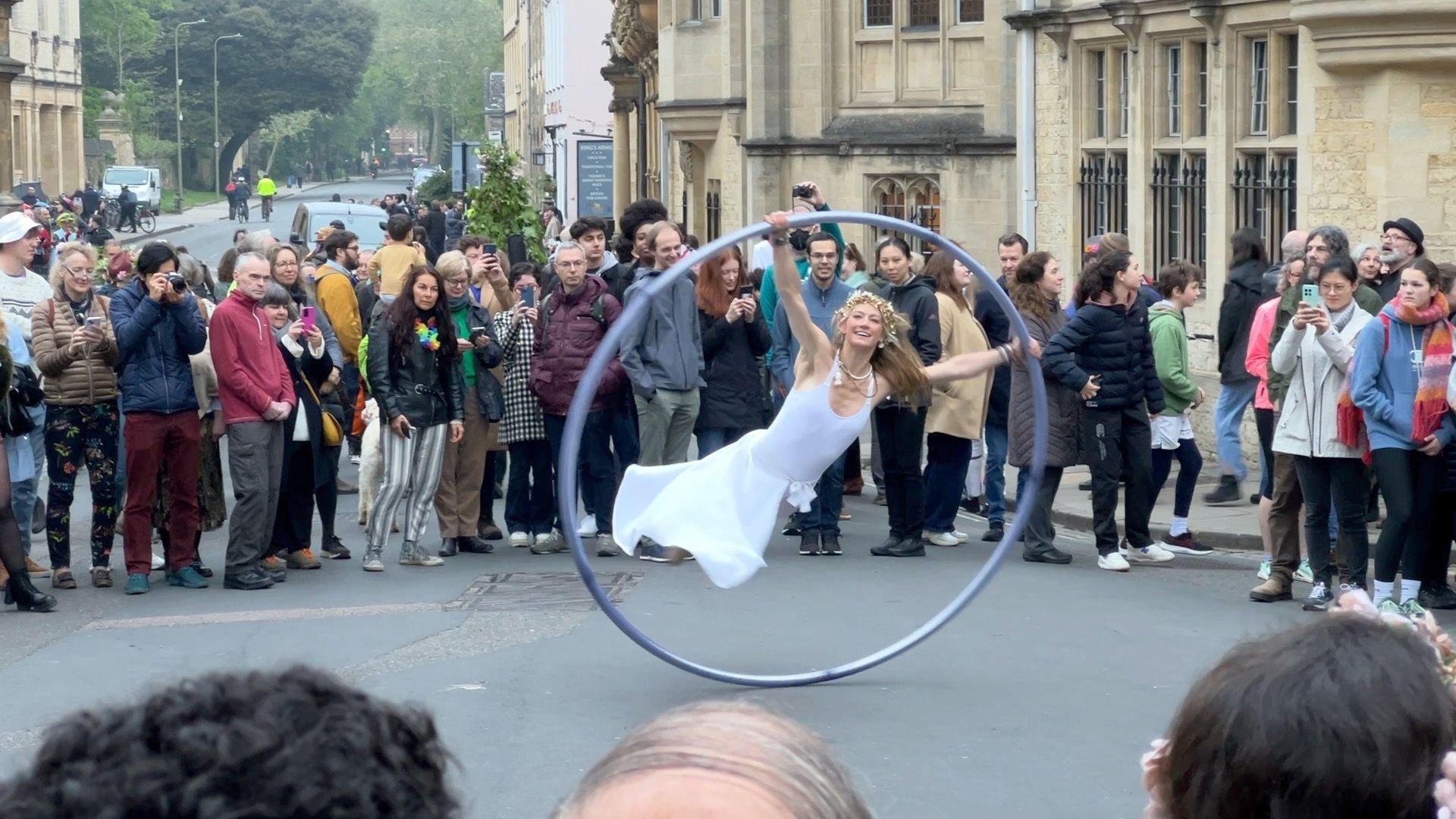 A woman dressed in white spinning in a large wheel