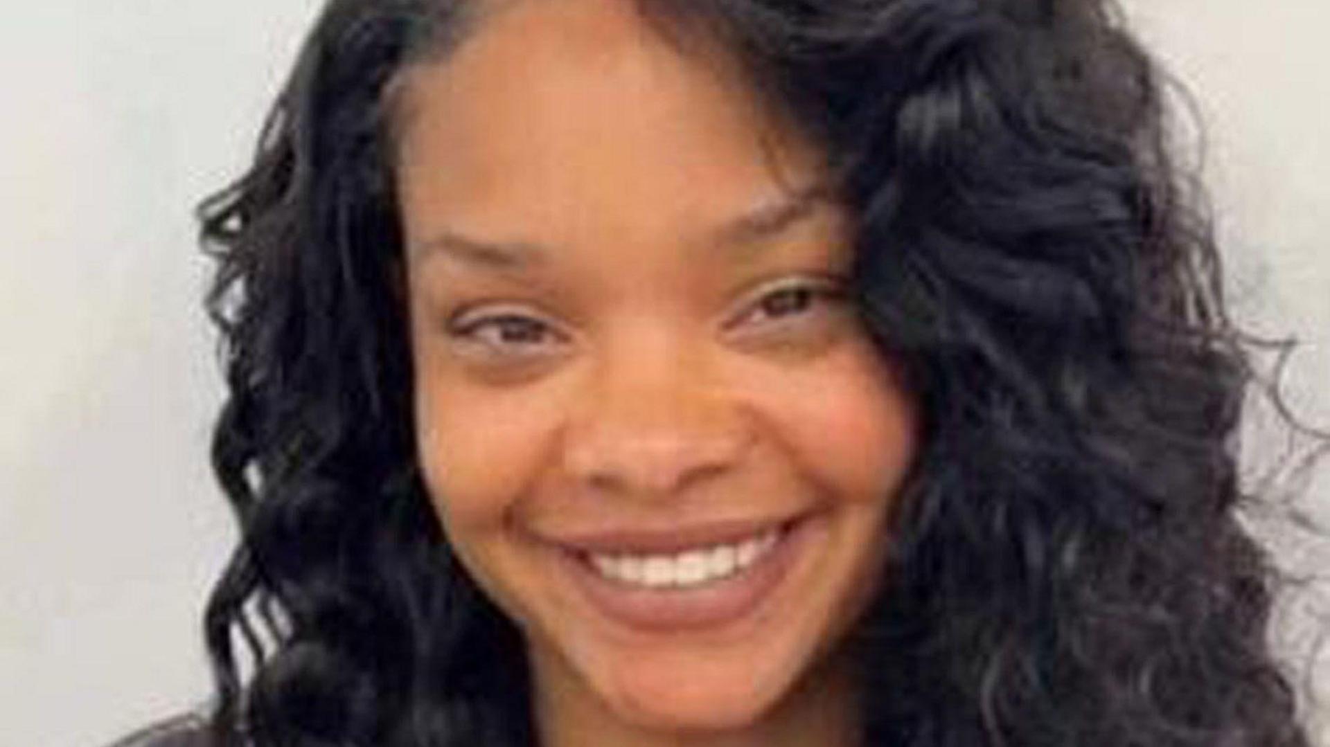 A close up of a smiling young woman with brown eyes and long curly dark hair.
