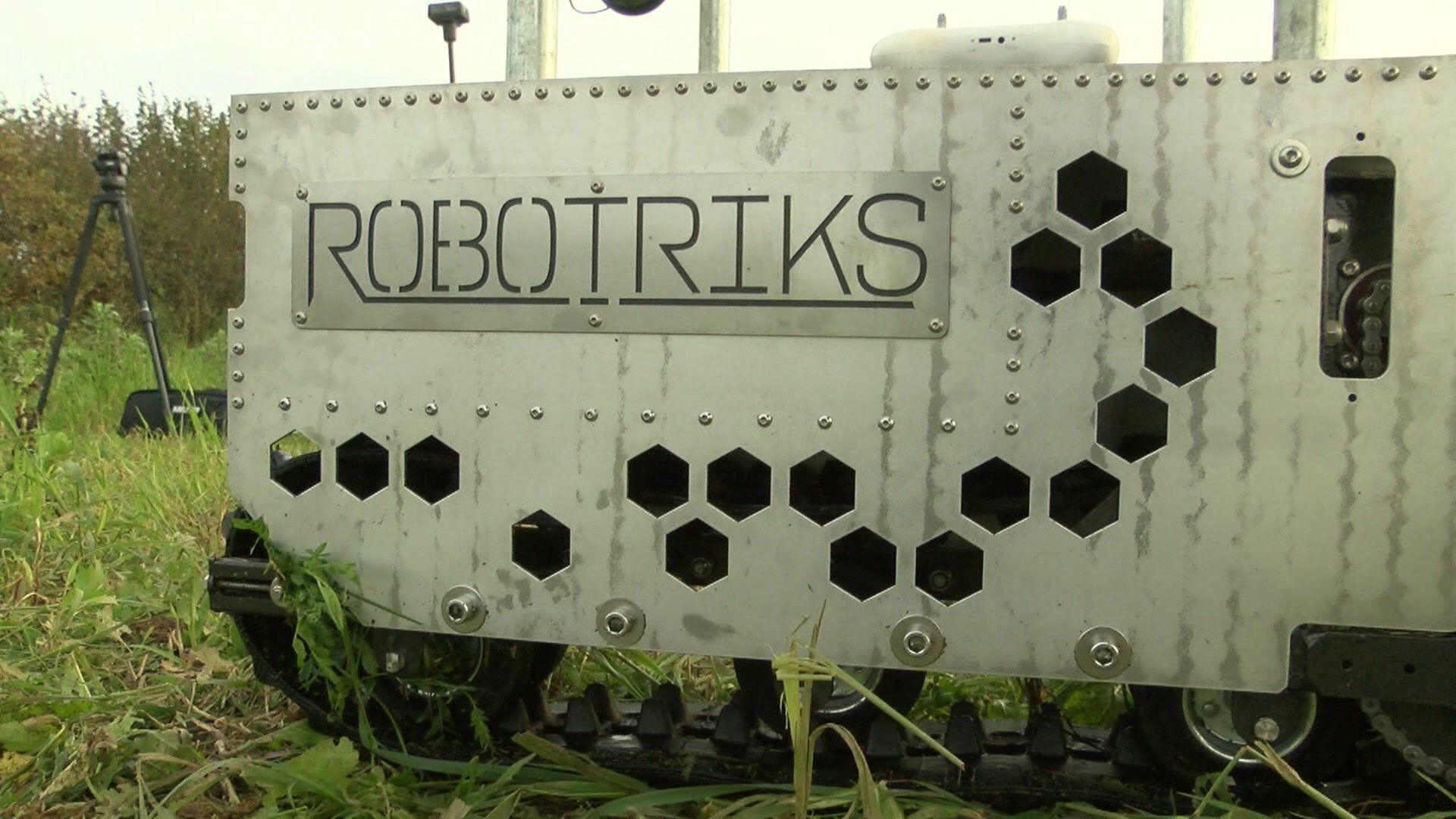 A metal sheet with the word Robotriks and some polygon cut outs in a field.