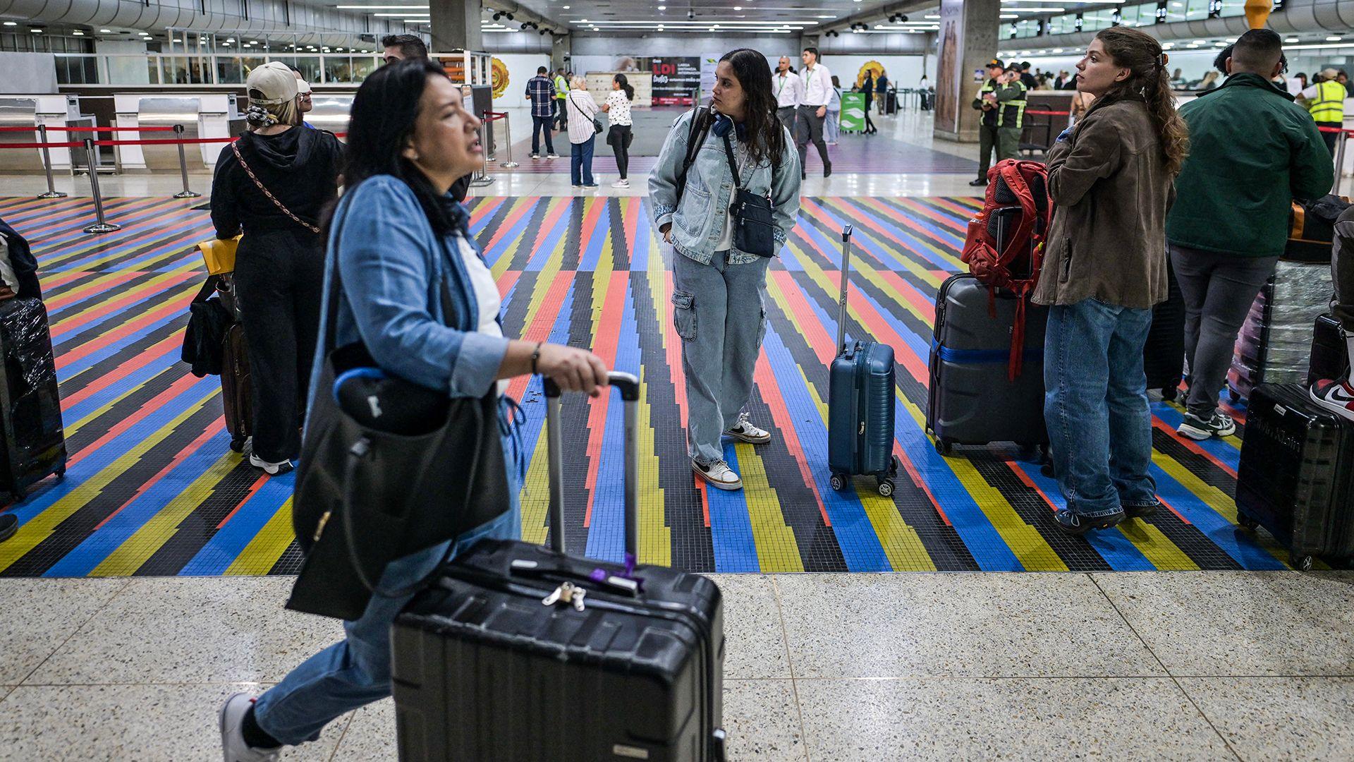 People queue to check in, with one person at the front wheeling a suitcase, at Simon Bolivar International Airport in Maiquetia, near Caracas, Venezuela, 26 November 2025