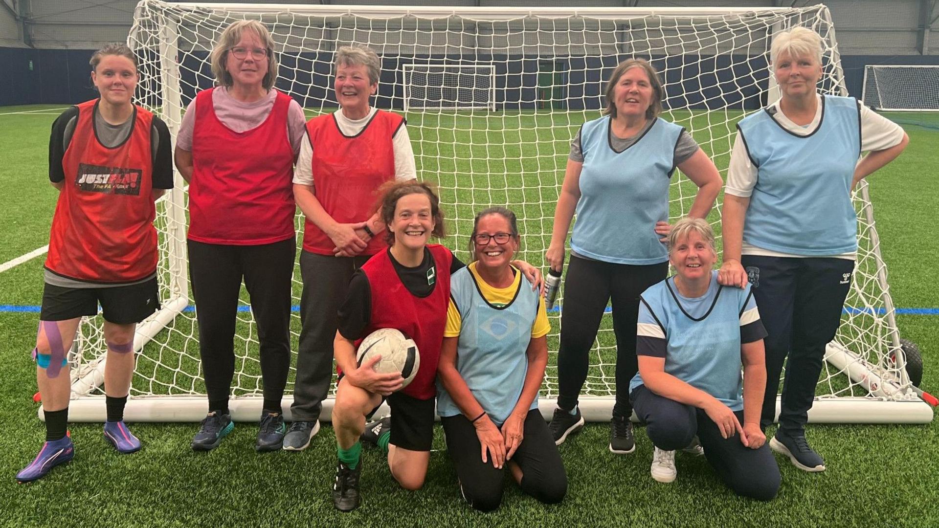 Coventry and District Walking Football Club showing eight women in front of a football goal with half wearing red tabards, the others blue tabards