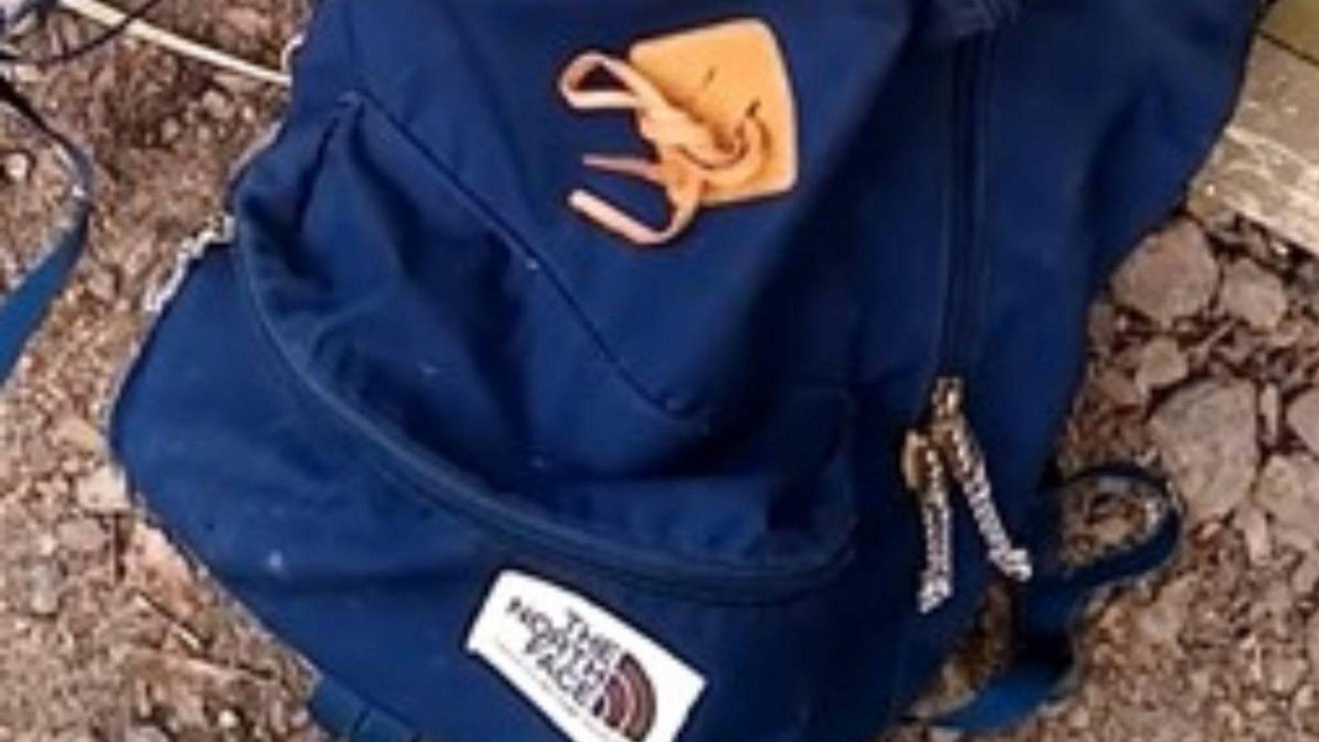 A dark blue The North Face rucksack on some dirt