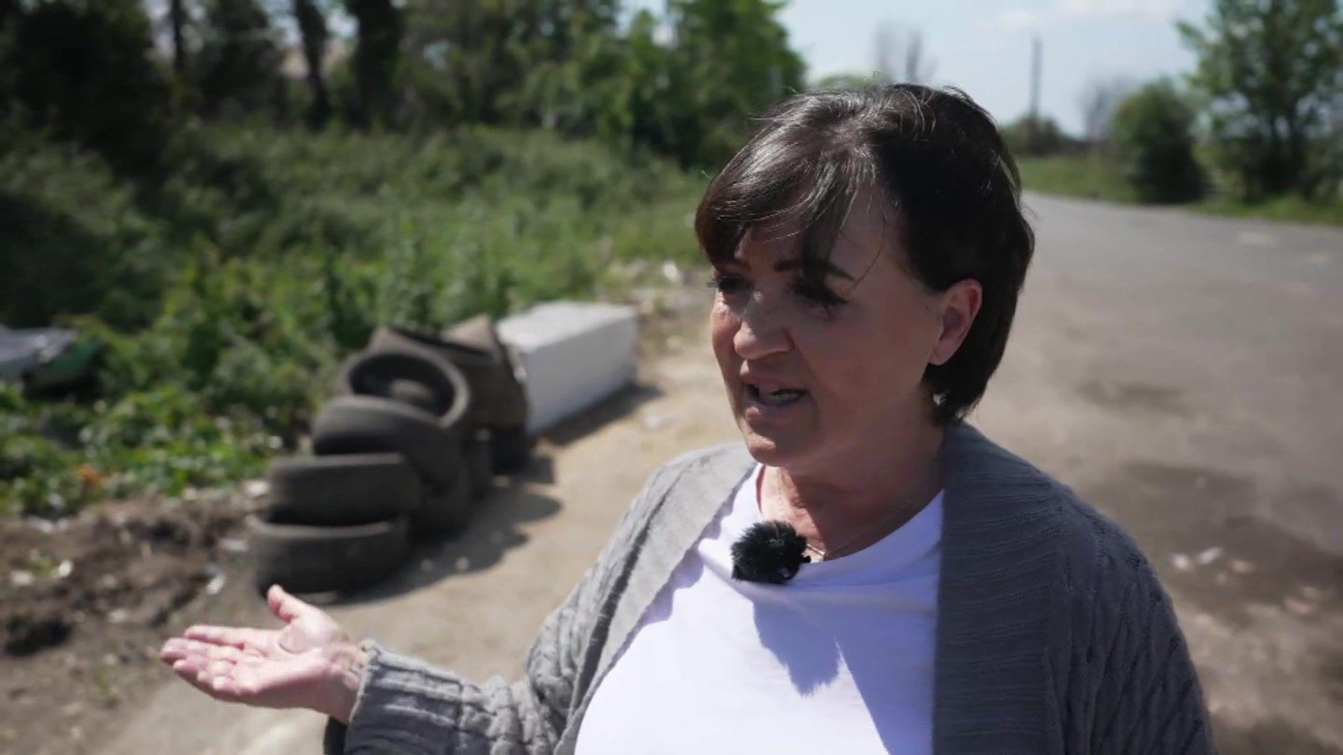 Kym Grant standing in front of a pile of rubbish including electrical items and tyres