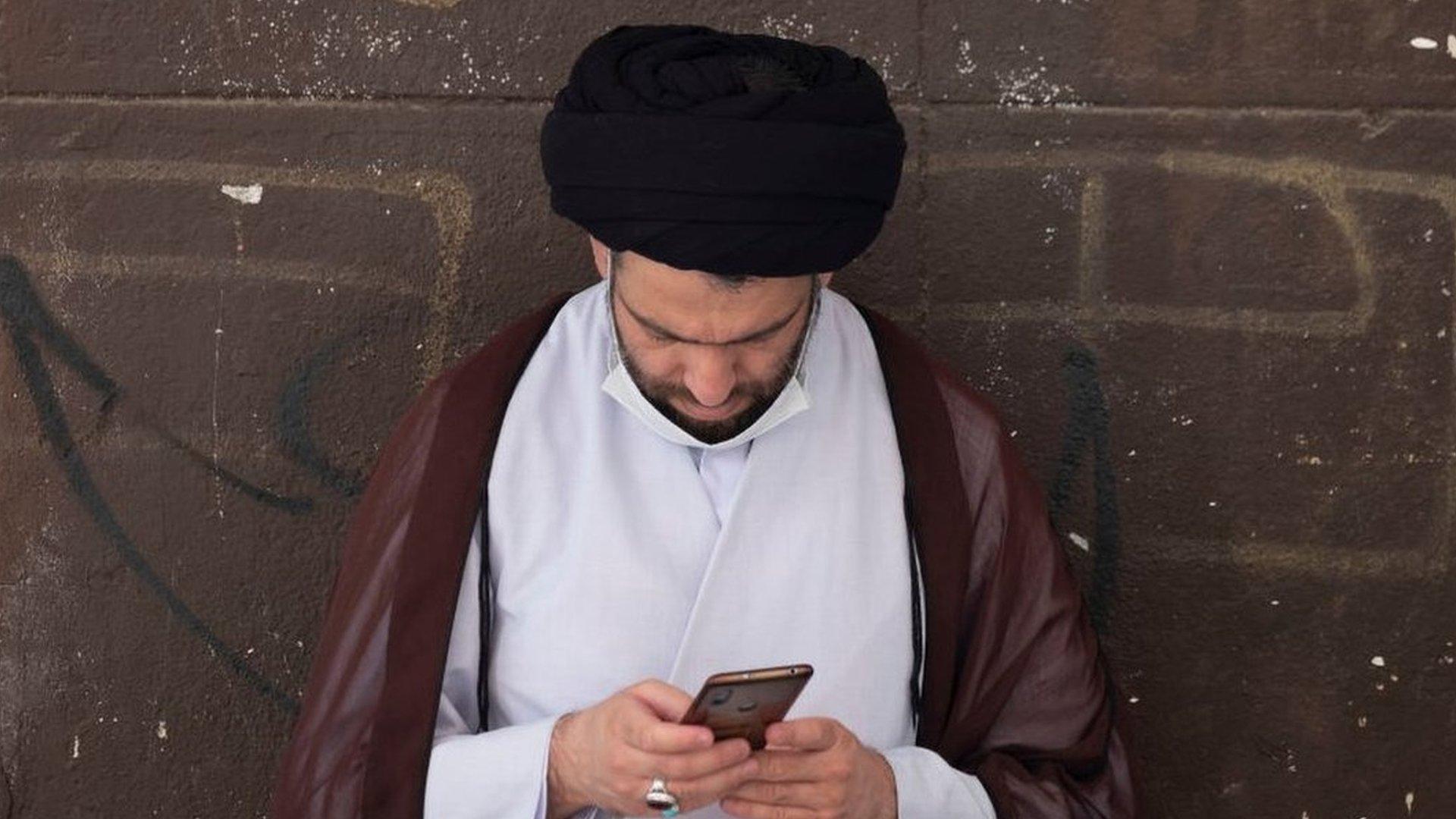 An Iranian cleric uses his smartphone